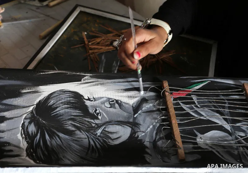 A Palestinian girl paints a picture at an atelier in Rafah in the southern Gaza Strip, February 9, 2015. Three Palestinian artists use the remains of houses which were destroyed during the 51 day Israeli recent war on Ga...