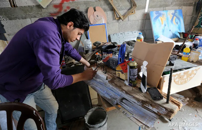 A Palestinian man paints on wood at an atelier in Rafah in the southern Gaza Strip, February 9, 2015. Three Palestinian artists use the remains of houses which were destroyed during the 51 day Israeli recent war on Gaza...