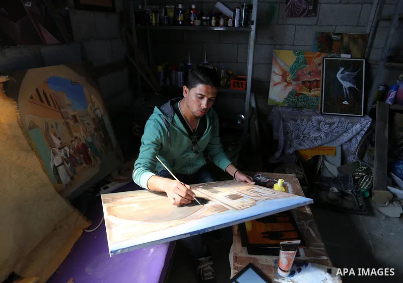 A Palestinian man paints a picture at an atelier in Rafah in the southern Gaza Strip, February 9, 2015. Three Palestinian artists use the remains of houses which were destroyed during the 51 day Israeli recent war on Gaz...
