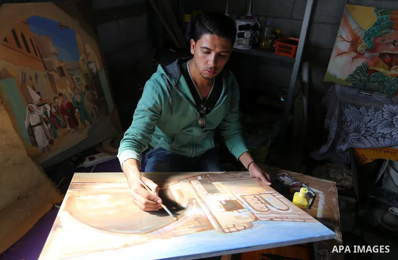 A Palestinian man paints a picture at an atelier in Rafah in the southern Gaza Strip, February 9, 2015. Three Palestinian artists use the remains of houses which were destroyed during the 51 day Israeli recent war on Gaz...