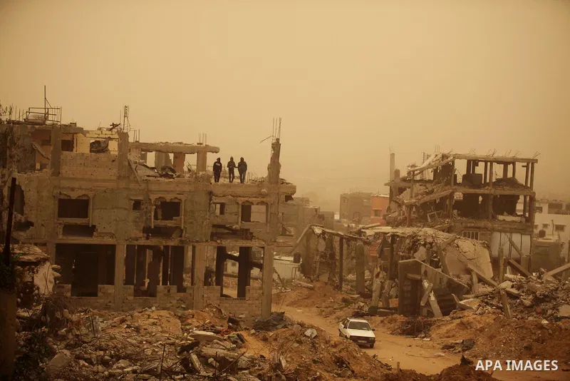 Palestinians stand on the remains of their destroyed house during a sandstorm, in al-Shijaiyah destrict in Gaza city on February 11, 2015. Photo by Ashraf Amra