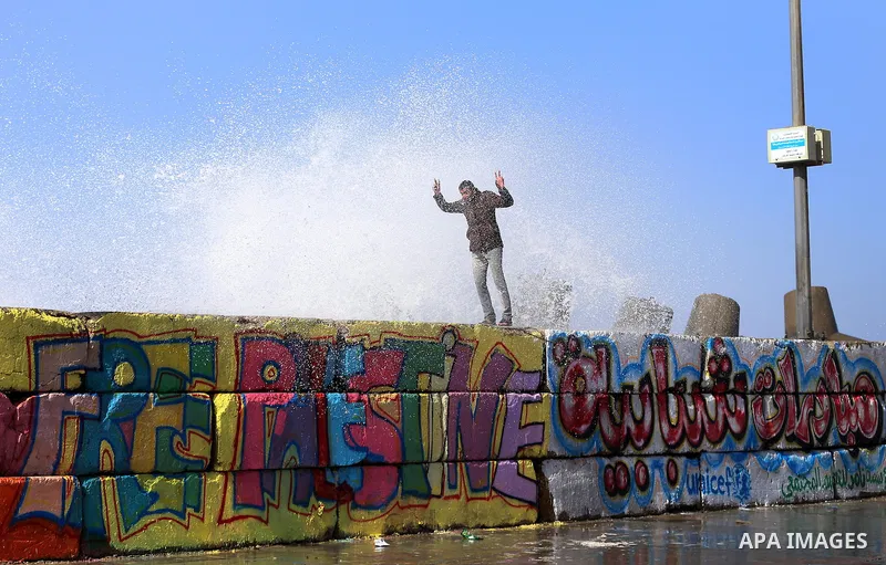 A Palestinian man stands on breaks as a huge wave crash over a sea wall at the Gaza seaport during a stormy day, east Gaza city on February 12, 2015. Photo by Yasser Qudih