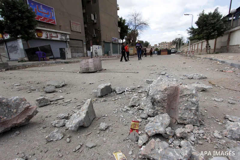 Egyptians walk at site of a bomb blast in front of a police station in the Ain Shams area in Cairo, 13 February 2015. Attacks on security forces have become common in Egypt, which is currently battling an insurgency in t...