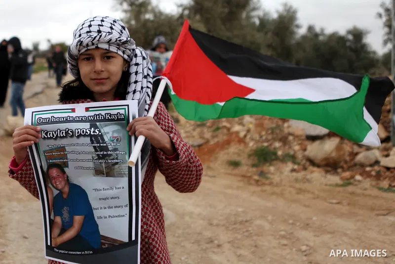 A Palestinian girl holds the picture of Islamic State captive Kayla Mueller during a demonstration against Jewish settlements in the West Bank village of Bilin, near Ramallah February 13, 2015. Photo by Shadi Hatem