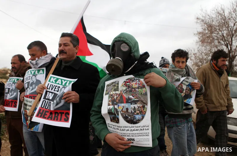 Palestinian and foreign activists hold pictures of the Muslim victims of the UNC shooting during a demonstration against Jewish settlements in the West Bank village of Bilin, near Ramallah February 13, 2015. Photo by Sha...
