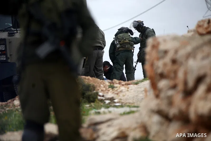 A Palestinian protester lies on the ground as he is detained by Israeli police and soldiers during clashes following a demonstration against Jewish settlements in the West Bank village of Bilin, near Ramallah February 13...