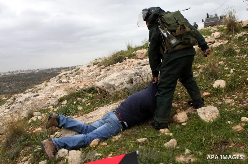 A Palestinian protester lies on the ground as he is detained by Israeli police and soldiers during clashes following a demonstration against Jewish settlements in the West Bank village of Bilin, near Ramallah February 13...