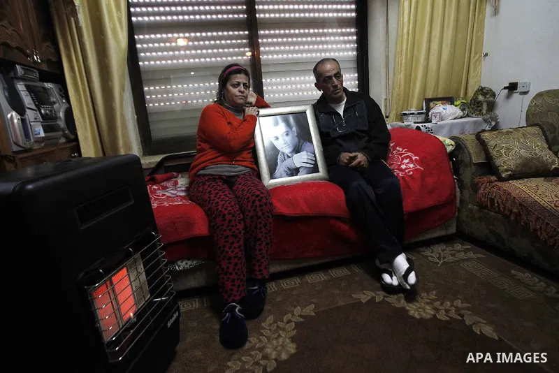 The parents of Arab-Israeli Muhammad Said Ismail Musallam sit next to a framed portrait of their son, who is captured by the Islamic State (IS) group allegedly for spying for Israel's Mossad foreign intelligence agency,...