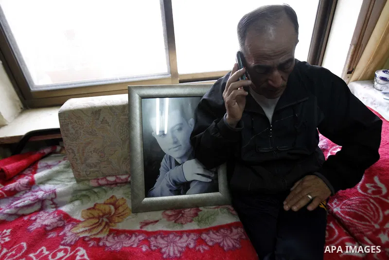 The father of Arab-Israeli Muhammad Said Ismail Musallam speaks on the phone as he sits next to a framed portrait of their son, who is captured by the Islamic State (IS) group allegedly for spying for Israel's Mossad for...