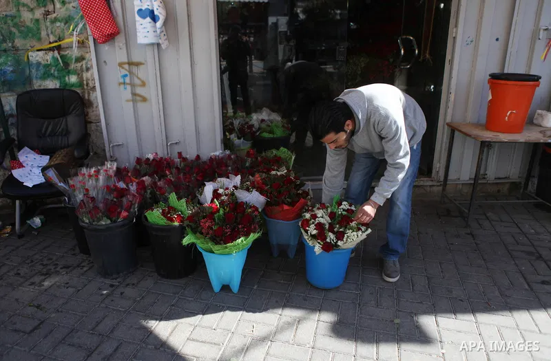 A Palestinian vendor sells a flowers on Valentine's day at his shop in the West Bank city of Ramallah, on Feb. 14, 2015. Valentine's Day is increasingly popular among younger Palestinians, many of whom have taken up the...