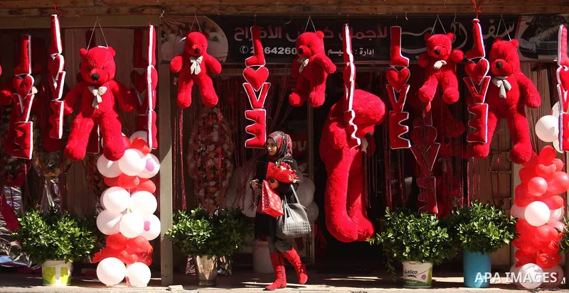 A Palestinian girl holds flowers in front of a shop displaying red teddy bears on Valentine's day in Gaza on February 14, 2015. Valentine's Day is increasingly popular in the region as people have taken up the custom of...