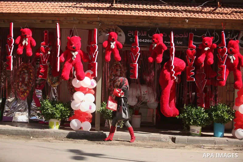 A Palestinian girl holds flowers in front of a shop displaying red teddy bears on Valentine's day in Gaza on February 14, 2015. Valentine's Day is increasingly popular in the region as people have taken up the custom of...