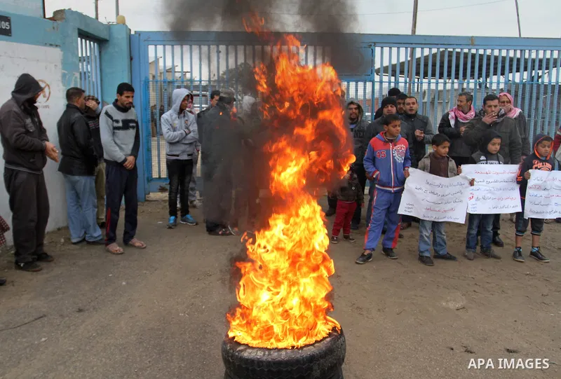Smoke rises from burning tyres as Palestinians shout during a protest calling for reconstruction of their houses that witnesses said were destroyed by Israeli shelling during a 50-day war last summer, outside a United Na...