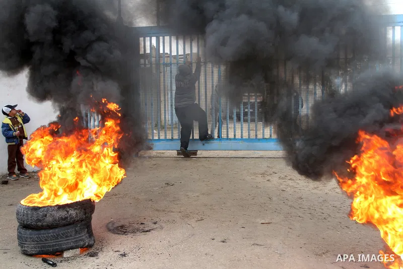 Smoke rises from burning tyres as Palestinians shout during a protest calling for reconstruction of their houses that witnesses said were destroyed by Israeli shelling during a 50-day war last summer, outside a United Na...