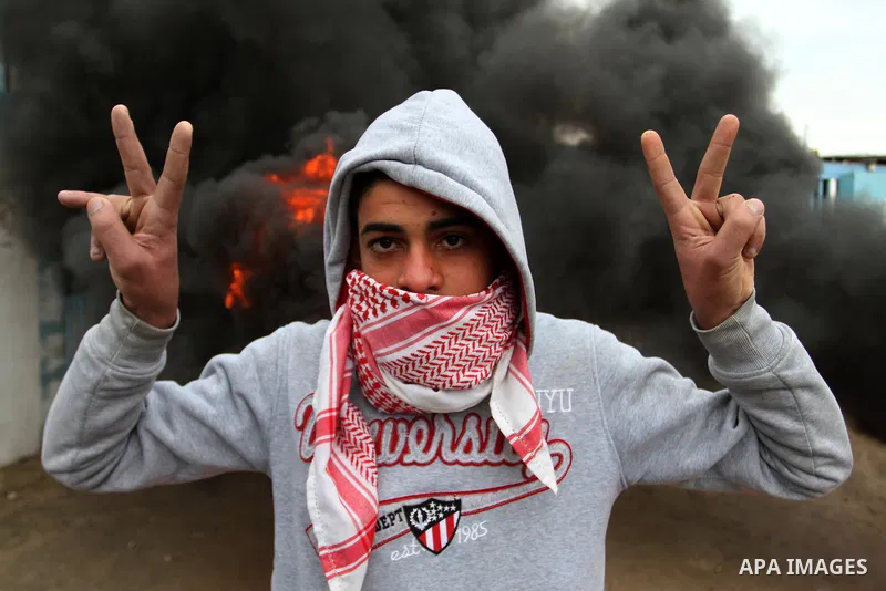 A Palestinian man standing near burning tyres takes part in a protest calling for reconstruction of houses that witnesses said were destroyed by Israeli shelling during a 50-day war last summer, outside a United Nations...