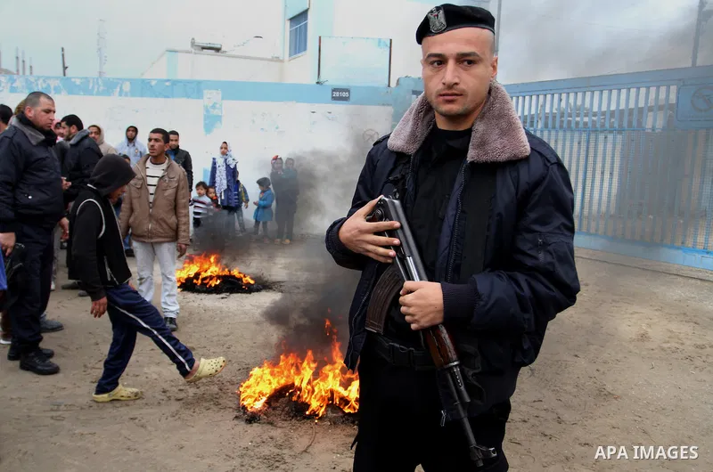 A Palestinian policeman loyal to Hamas stands guard near burning tyres during a protest by Palestinians calling for reconstruction of their houses that witnesses said were destroyed by Israeli shelling during a 50-day wa...