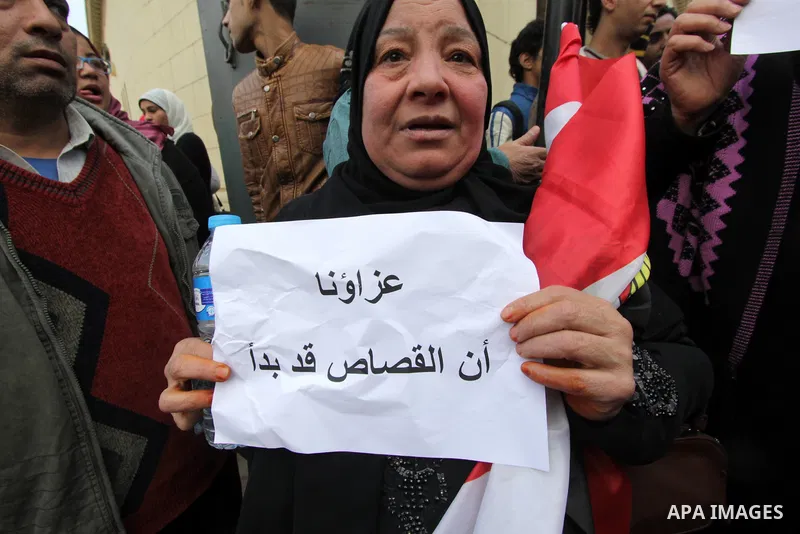 An Egyptian woman holds a placard with Arabic inscription reading 'We are consoled as retribution began' to denounce the killing of Egyptian Christians in Libya, outside the Coptic Cathedral of Saint Marcos, in Cairo, Eg...