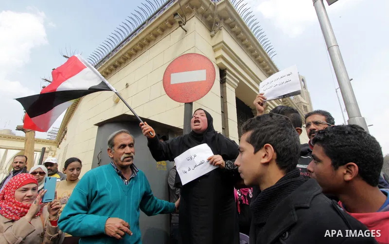 An Egyptian woman holds a placard with Arabic inscription reading 'We are consoled as retribution began' to denounce the killing of Egyptian Christians in Libya, outside the Coptic Cathedral of Saint Marcos, in Cairo, Eg...