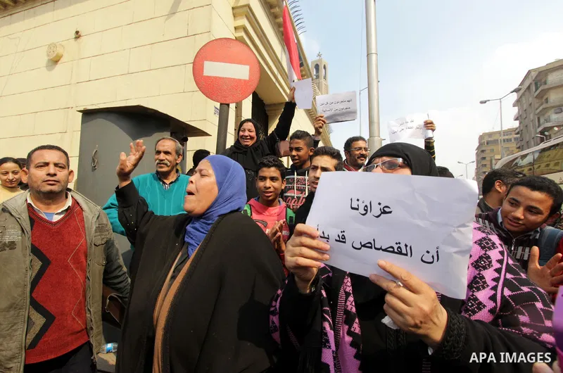 An Egyptian woman holds a placard with Arabic inscription reading 'We are consoled as retribution began' to denounce the killing of Egyptian Christians in Libya, outside the Coptic Cathedral of Saint Marcos, in Cairo, Eg...