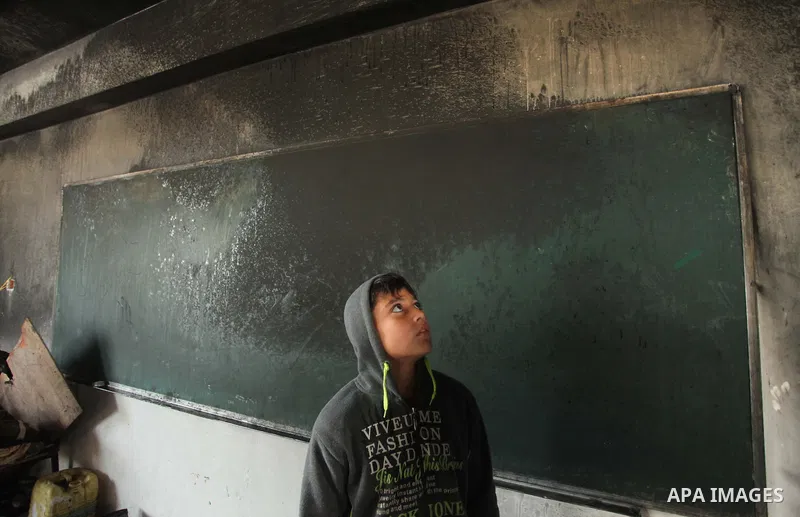 A Palestinian boy looks on as he inspects a burnt classroom at a UN-run school sheltering Palestinians, whose houses were destroyed by what witnesses said was Israeli shelling during a 50-day war last summer, in Biet Han...