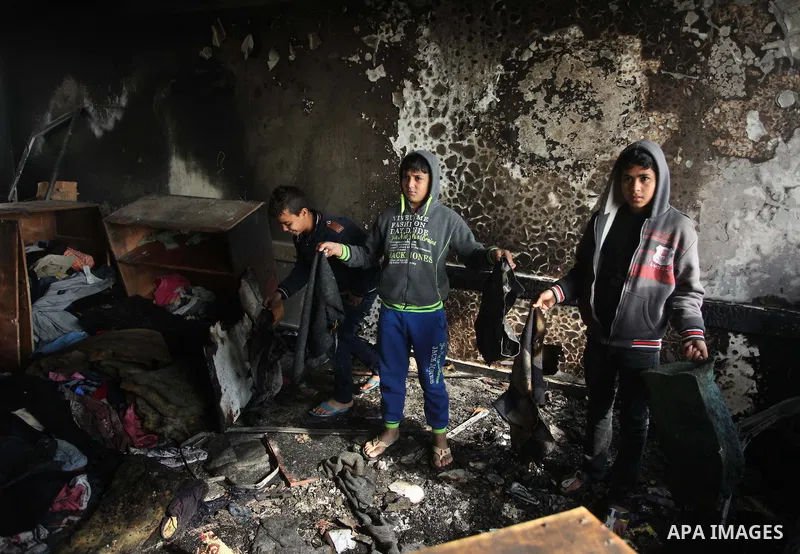 Palestinian men inspect a burnt classroom at a UN-run school sheltering Palestinians, whose houses were destroyed by what witnesses said was Israeli shelling during a 50-day war last summer, in Biet Hanoun in the norther...
