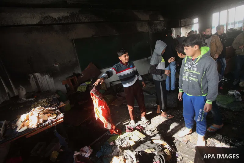 Palestinian men inspect a burnt classroom at a UN-run school sheltering Palestinians, whose houses were destroyed by what witnesses said was Israeli shelling during a 50-day war last summer, in Biet Hanoun in the norther...