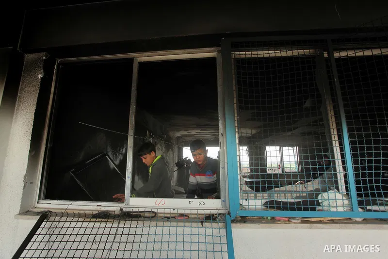 Palestinian men inspect a burnt classroom at a UN-run school sheltering Palestinians, whose houses were destroyed by what witnesses said was Israeli shelling during a 50-day war last summer, in Biet Hanoun in the norther...