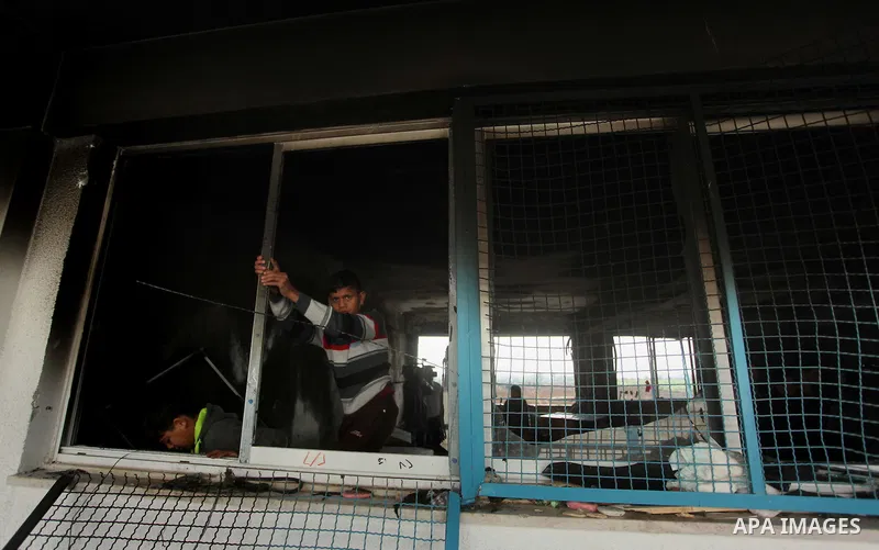Palestinian men inspect a burnt classroom at a UN-run school sheltering Palestinians, whose houses were destroyed by what witnesses said was Israeli shelling during a 50-day war last summer, in Biet Hanoun in the norther...