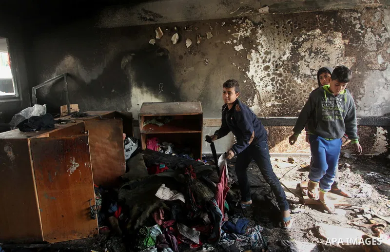Palestinian men inspect a burnt classroom at a UN-run school sheltering Palestinians, whose houses were destroyed by what witnesses said was Israeli shelling during a 50-day war last summer, in Biet Hanoun in the norther...
