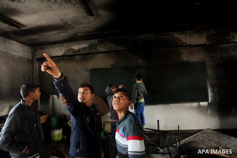 Palestinian men inspect a burnt classroom at a UN-run school sheltering Palestinians, whose houses were destroyed by what witnesses said was Israeli shelling during a 50-day war last summer, in Biet Hanoun in the norther...