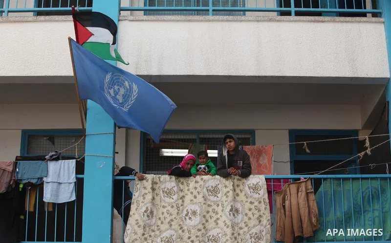 Palestinians stand outside classrooms at a United Nations (UN) run school sheltering Palestinians, whose houses were destroyed in the 50- day-war Israeli last summer, during a funeral of boy Izz eldeen Al-Kafarana, 9 mon...