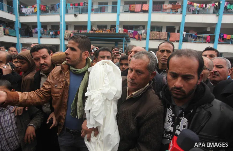 A relative carries the body of Palestinian boy Izz eldeen Al-Kafarana, 9 months old, during his funeral at a UN-run school where he died in Biet Hanoun in the northern Gaza Strip February 17, 2015. Palestinian health off...