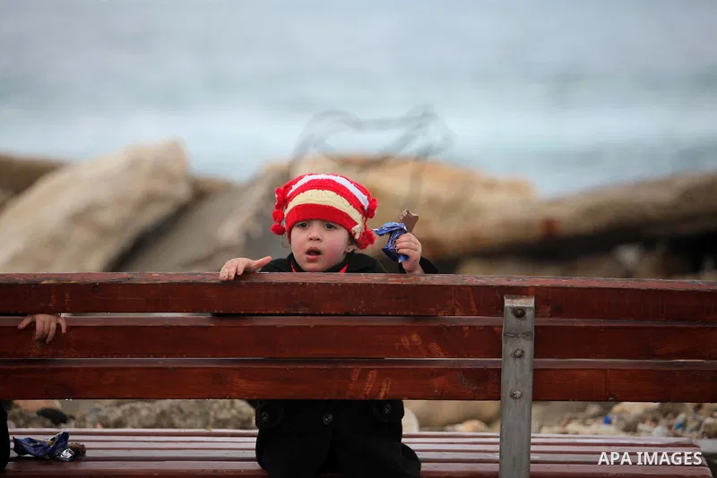 A Palestinian girl sits at the seaport near the coast of Gaza city during a rainy day, February 18, 2015. Photo by Ashraf Amra