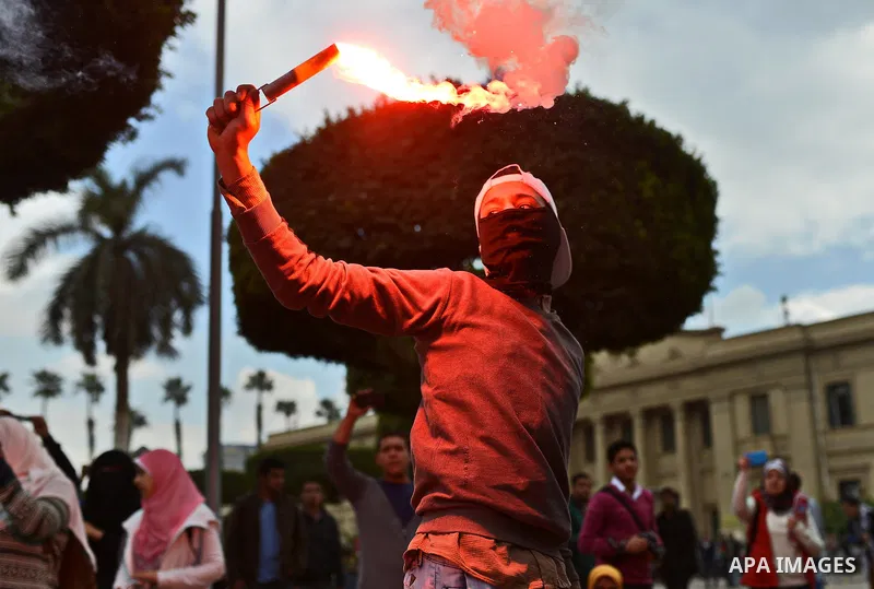 An Egyptian student who supports ousted President Mohamed Morsi and the Muslim Brotherhood lights up a flare as others protest against the military rule, in Cairo University on February 18, 2015. Due to the escalation of...