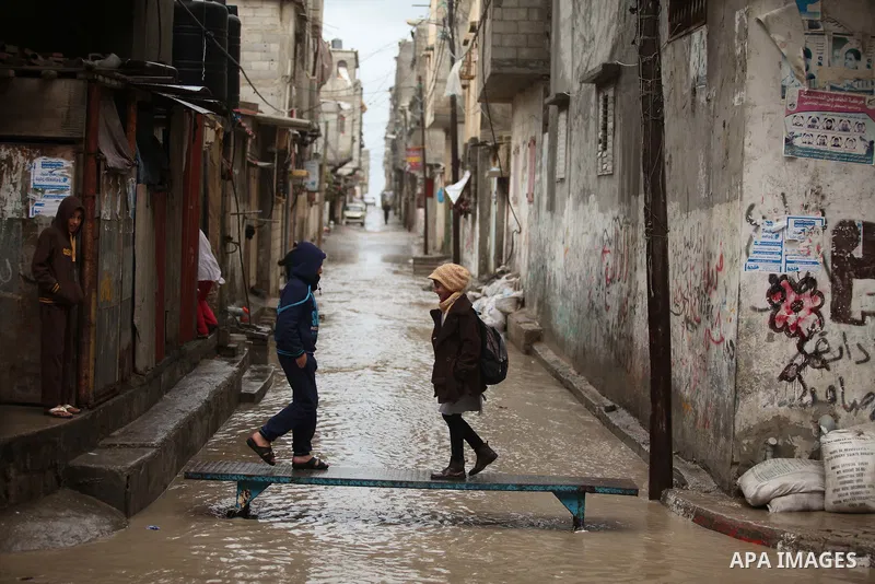 Palestinian students walk in a flooded street during a rainy day at Shati refugee camp in Gaza City, Feb. 19, 2015. Photo by Ashraf Amra