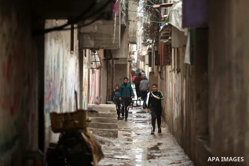 Palestinian students walk in a flooded street during a rainy day at Shati refugee camp in Gaza City, Feb. 19, 2015. Photo by Ashraf Amra