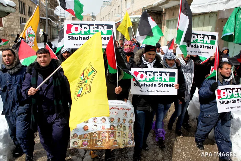 Palestinian protesters hold banners during a demonstration against the closure of Shuhada street to Palestinians, in the West Bank city of Hebron February 20, 2015. Dozens of protesters, including foreign activists, gath...