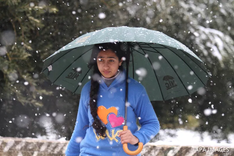 A Palestinian girl holding umbrella walks as snow falls in the West Bank city of Nablus February 20, 2015. A heavy winter storm hit parts of the Middle East on Friday, shutting down roads leading in and out of Jerusalem...