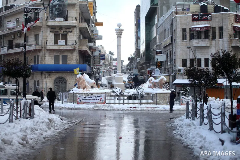 Palestinians walk in a street coverd with snow in the center of the West Bank city of Ramallah on February 20, 2015. A heavy winter storm hit parts of the Middle East on Friday, shutting down roads leading in and out of...