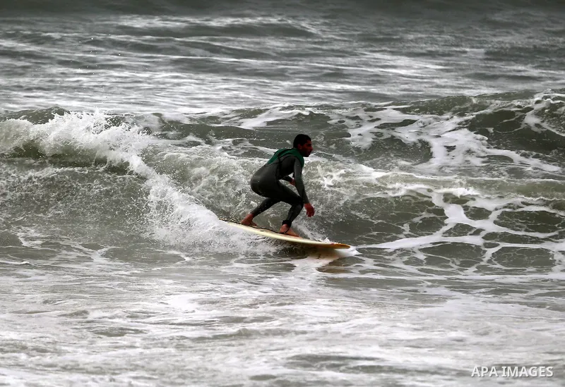A Palestinian youth surfs in the Mediterranean Sea off the coast of Gaza City, during rainy weather, Feb. 21, 2015. A heavy winter storm descended on parts of the Middle East. Photo by Yasser Qudih