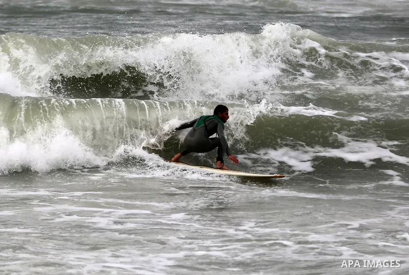 A Palestinian youth surfs in the Mediterranean Sea off the coast of Gaza City, during rainy weather, Feb. 21, 2015. A heavy winter storm descended on parts of the Middle East. Photo by Yasser Qudih