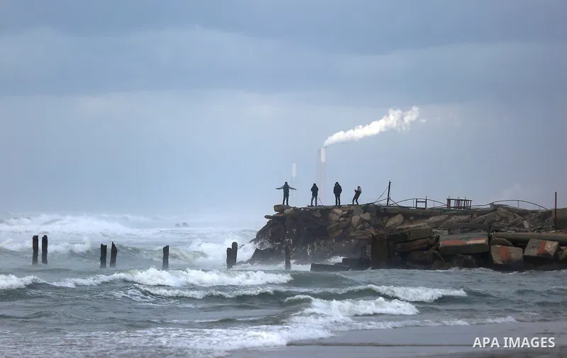 Palestinians enjoy at the Mediterranean Sea off the coast of Gaza City, during rainy weather, Feb. 21, 2015. A heavy winter storm descended on parts of the Middle East. Photo by Yasser Qudih