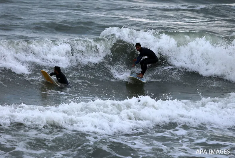 Palestinian youths surf in the Mediterranean Sea off the coast of Gaza City, during rainy weather, Feb. 21, 2015. A heavy winter storm descended on parts of the Middle East. Photo by Yasser Qudih