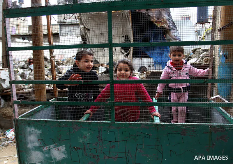 Palestinian children play on the remains of destroyed houses, which were damaged during the recent Israeli war, in Rafah in the southern Gaza strip, February 22, 2015. At least 100,000 Palestinians are still living witho...