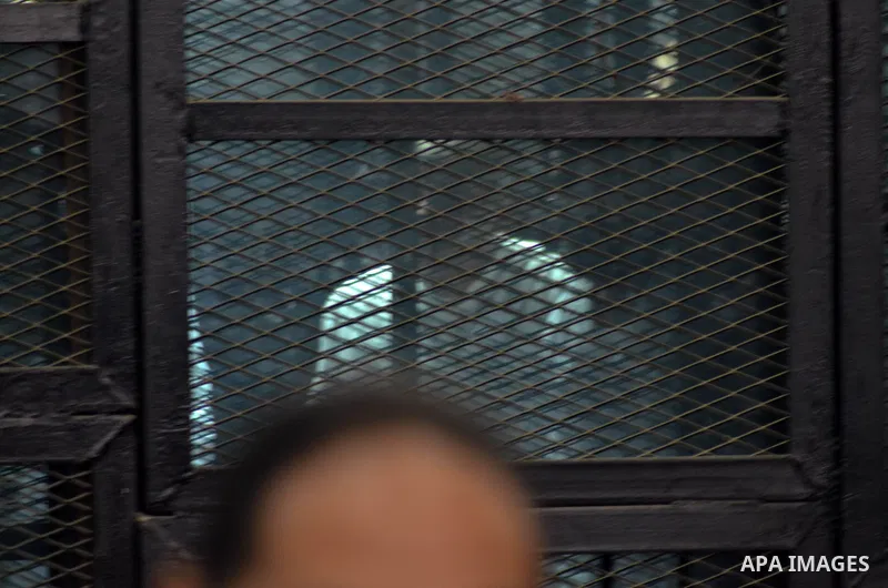 Fellow defendants of Egyptian activist Alaa Abdel Fattah (unseen) stand behind bars as they wait for their verdict in their trial at a police institute in Cairo's Tora prison on February 23, 2015. Fattah, a leading dissi...