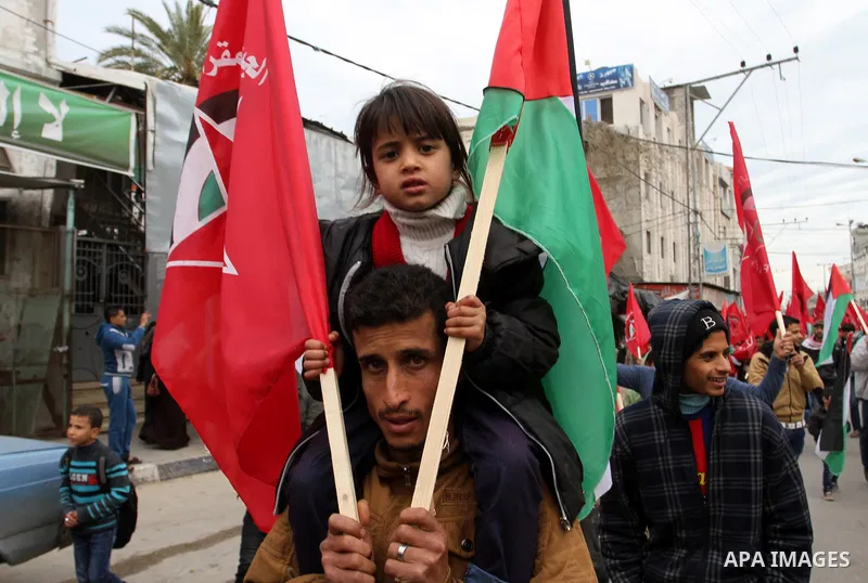 A Palestinian man carries his son during a rally marking the 46th anniversary of the founding of the Democratic Front for the Liberation of Palestine (DFLP), in Rafah in the southern Gaza Strip February 23, 2015. Photo b...