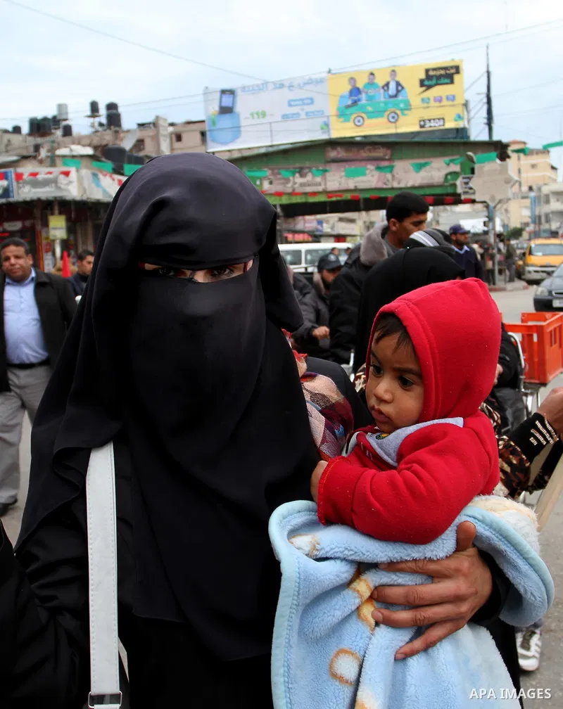 A Palestinian woman carries her son during a rally marking the 46th anniversary of the founding of the Democratic Front for the Liberation of Palestine (DFLP), in Rafah in the southern Gaza Strip February 23, 2015. Photo...