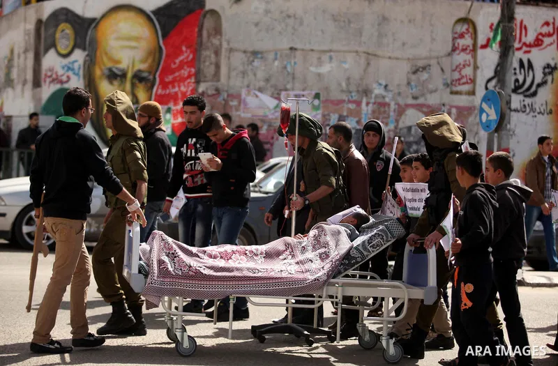 Palestinians enact a scene of Israeli soldiers pushes a boy lying in a bed in reference to Khaled al-Sheikh, a 14-years-old Palestinian boy jailed in an Israeli prison, during a rally calling for his release in Gaza City...
