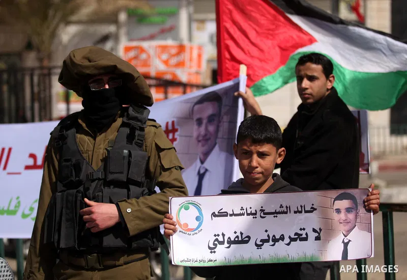 A Palestinian boy holds a banner with portrait of Khaled al-Sheikh, a 14-years-old Palestinian boy jailed in an Israeli prison, during a rally calling for his release in Gaza City February 25, 2015. According to the al-S...
