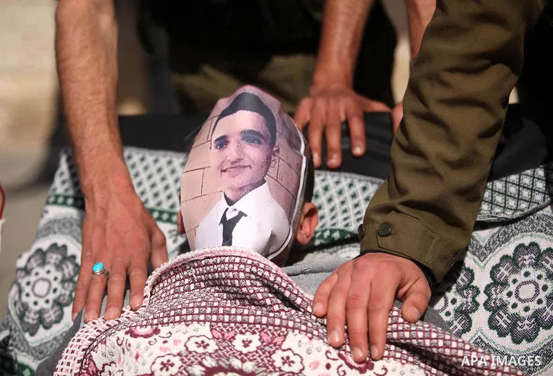 Palestinians enact a scene of Israeli soldiers and a boy lying in a bed in reference to Khaled al-Sheikh, a 14-years-old Palestinian boy jailed in an Israeli prison, during a rally calling for his release in Gaza City Fe...